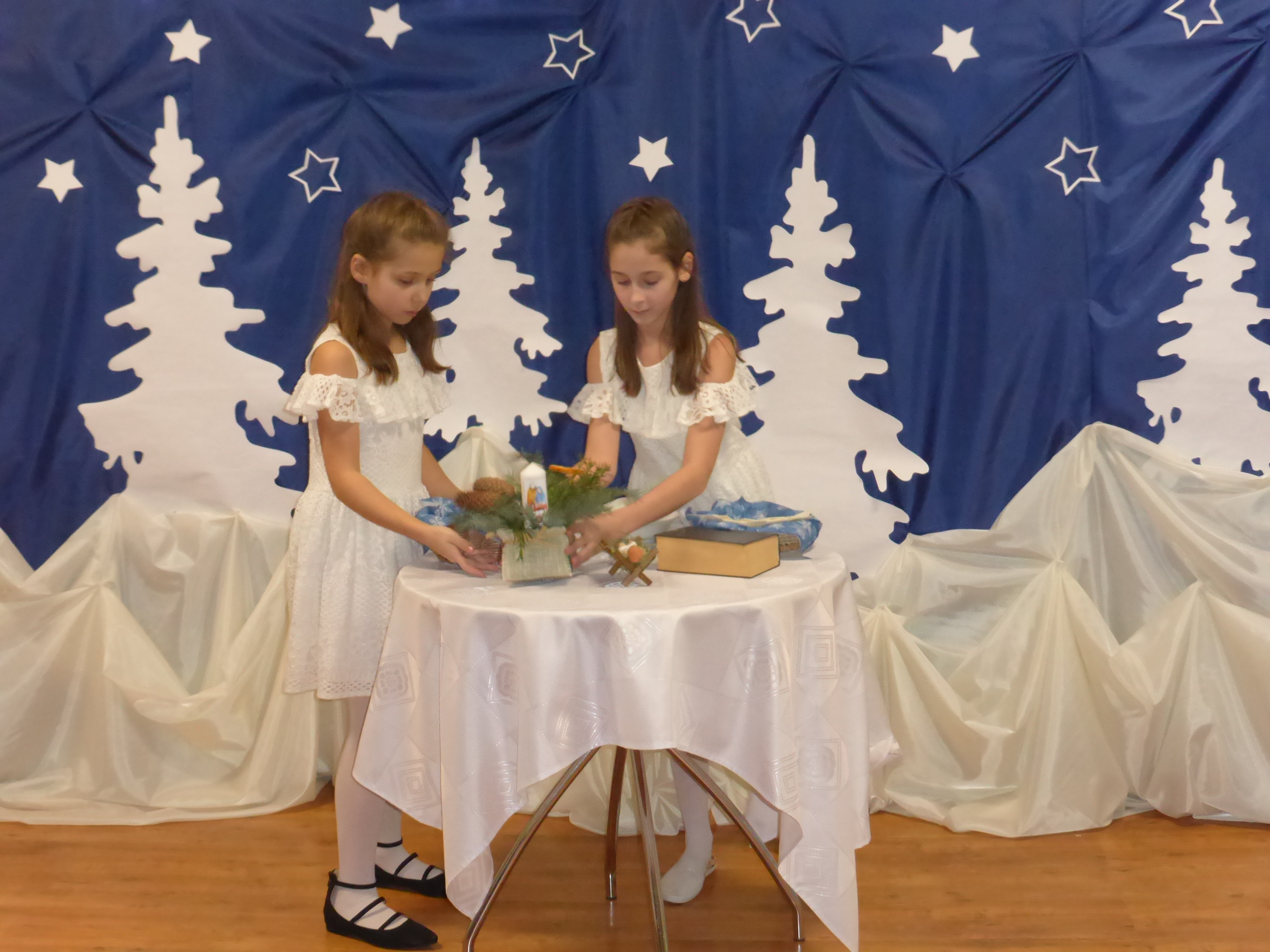 Na zdjęciu dziewczynki występujące w przedstawieniu nakrywają do stołu