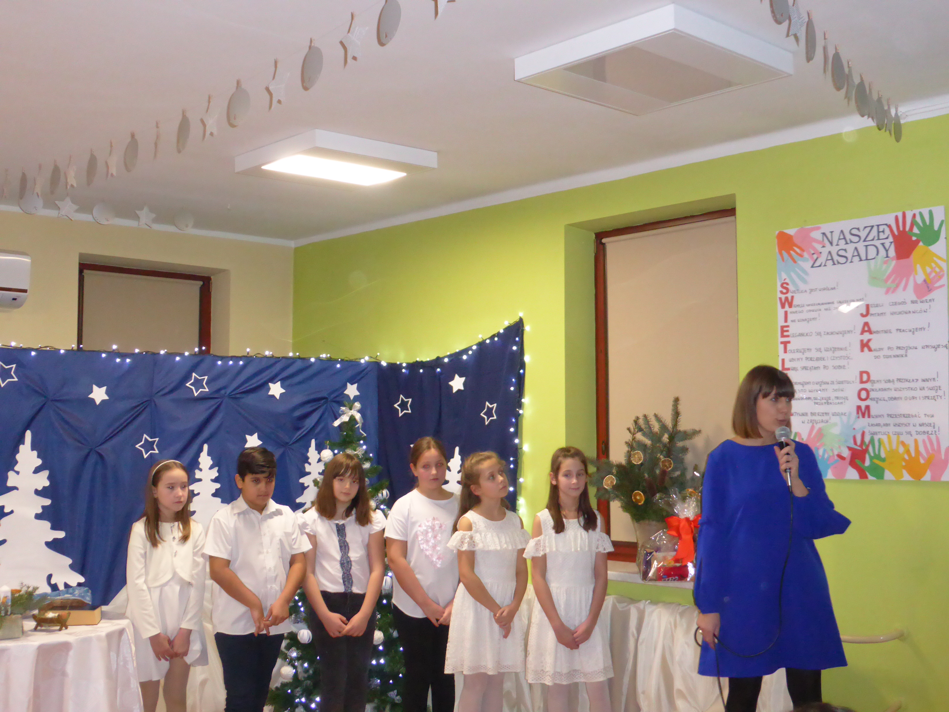 Na zdjęciu dzieci na scenie, przed nimi kierownik Działu Profilaktyki Środowiskowej OPS w Andrychowie - Marta Kajzer