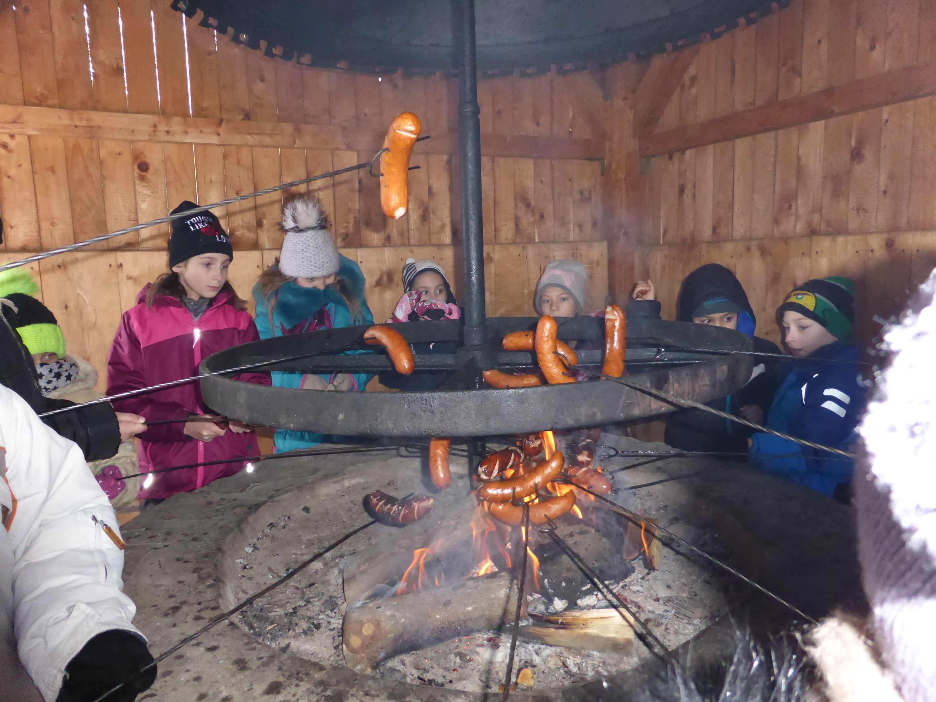 Na zdjęciu dzieci pieką kiełbaski nad ogniskiem