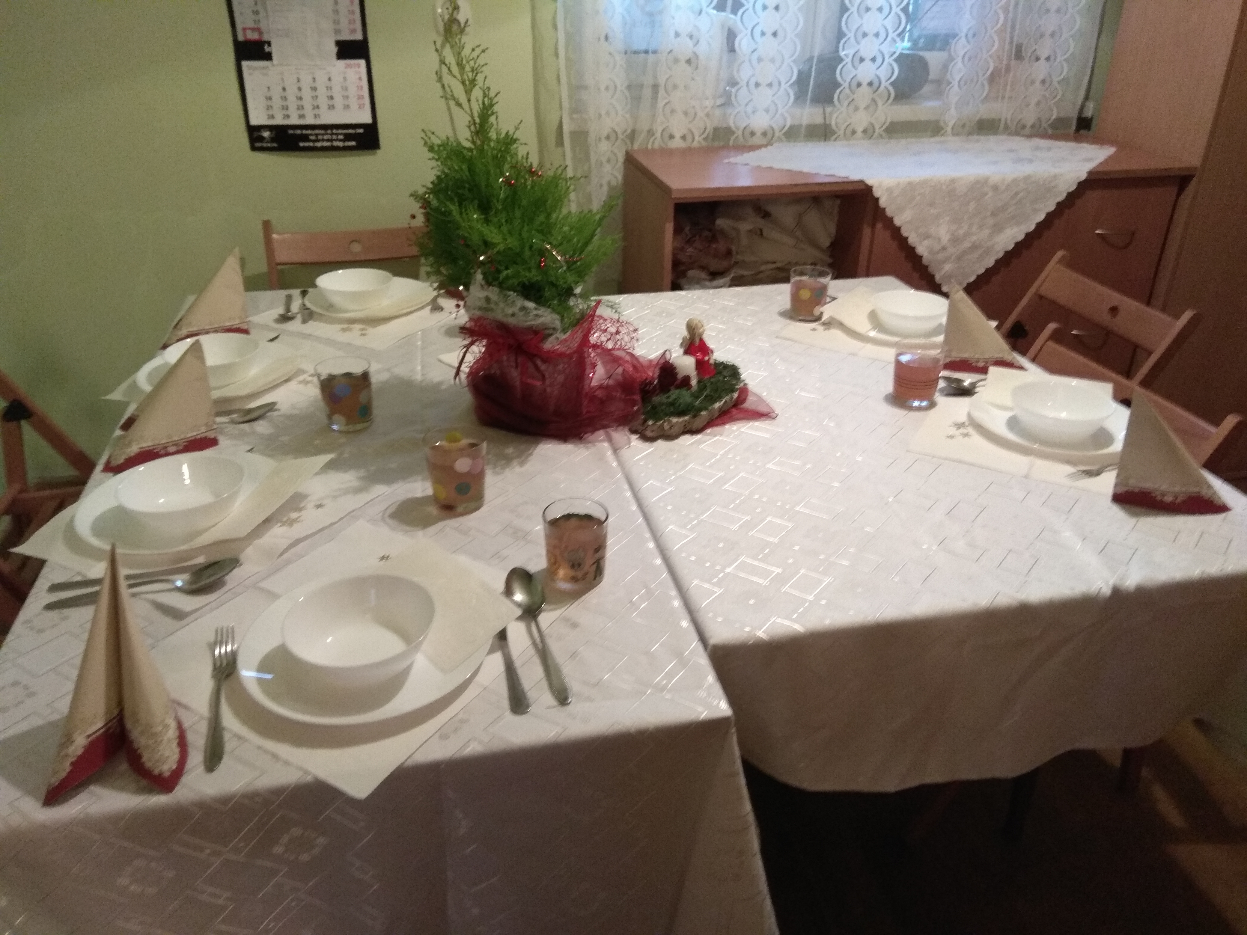 Na zdjęciu stół nakryty białym obrusem, na nim świąteczny stroik