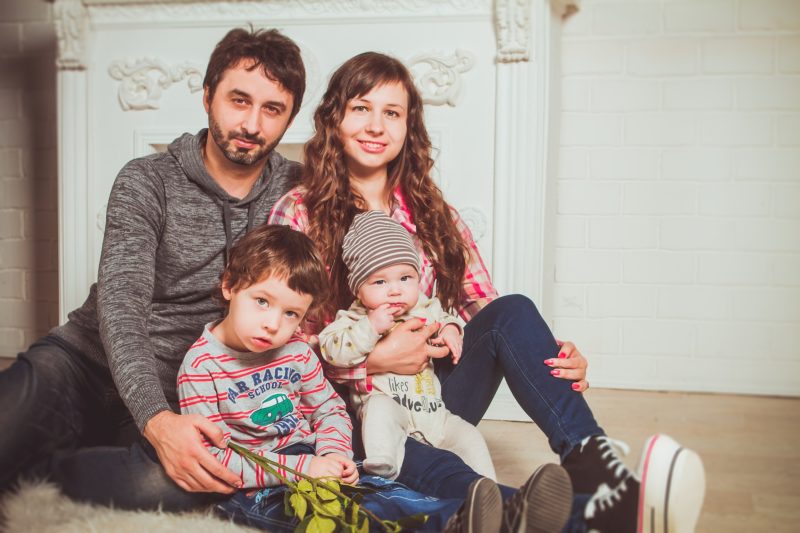 Rodzina - rodzice i dwoje dzieci, wszyscy siedzą razem na dywanie przy kominku i przytulają się