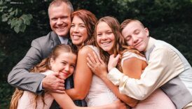 Rodzice i troje nastoletnich dzieci przytuleni do siebie