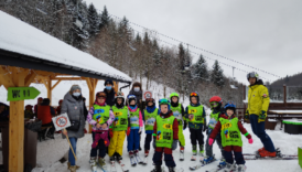 Dzieci na nartach pozują wspólnie z organizatorami akcji informacyjnej do zdjęcia