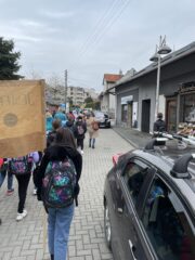 Dzieci idą ulicą, uczestniczą w marszu niosąc transparenty