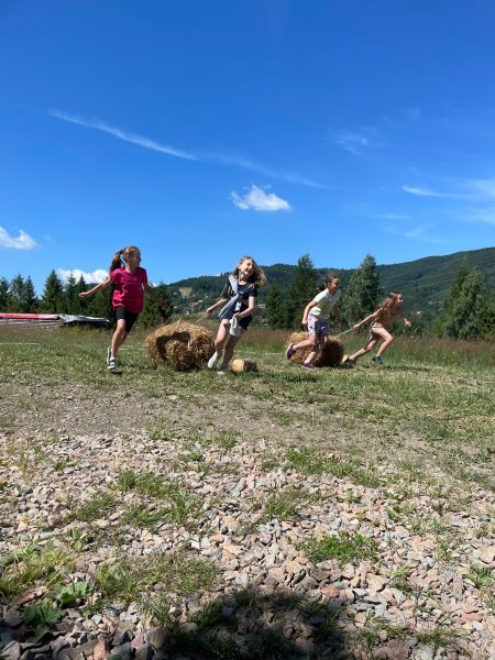 dziewczynki biegną z belami siana