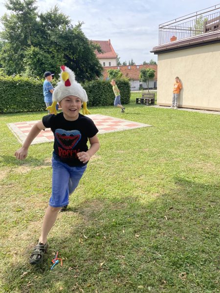 dziecko biegnie z czapka w kształcie kury na głowie