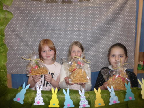 dziewczynki z własnoręcznie wykonanymi barankami i zajączkami wielkanocnymi, przed nimi papierowa girlanda z zajączków 