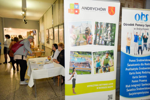 Roll-upy promujące Gminę Andrychów i Ośrodek Pomocy Społecznej w Andrychowie, obok osoby wpisujące się na listę uczestników konferencji