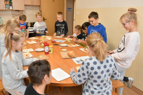 Dzieci zebrane wokół stołu robią kanapki