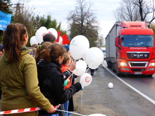 Dzieci z balonami z logo kampanii, na drugim planie ciężarówka