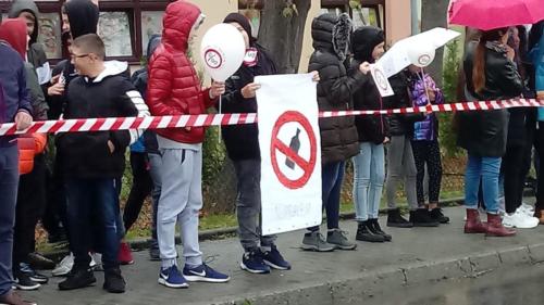 Uczniowie trzymają plakat ze znakiem z przekreśloną butelką