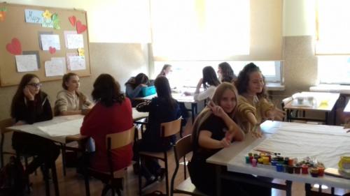 Uczniowie w szkole siedzą przy stolikach w małych grupach