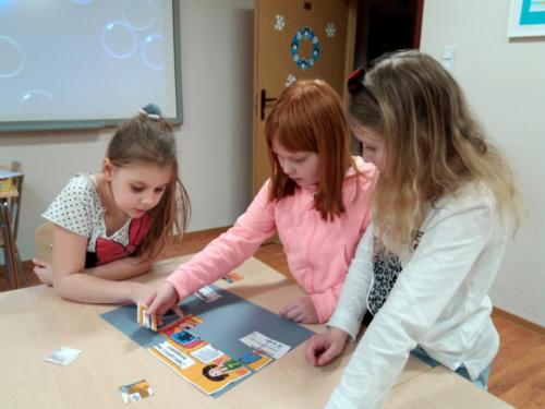 Grupa dziewczynek wspólnie układa puzzle profilaktyczne