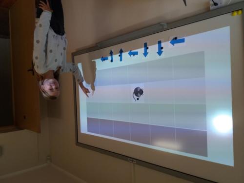 Dziewczynka uczy się programowania na tablicy interaktywnej