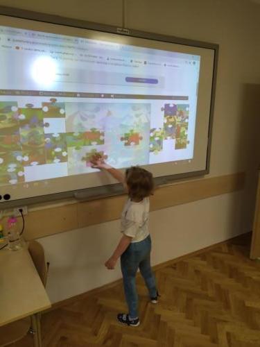 dziewczynka układa kolorowe puzzle z dinozaurami