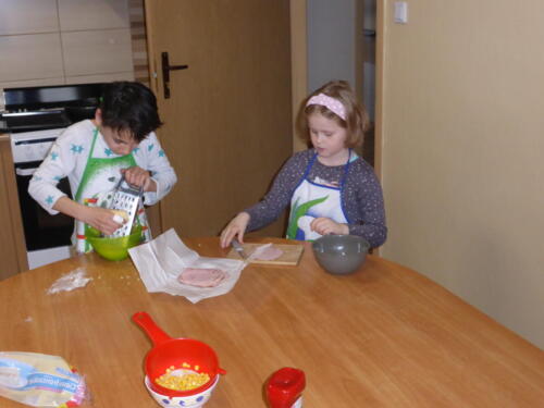 dzieci przygotowują ser i szynkę do pizzy