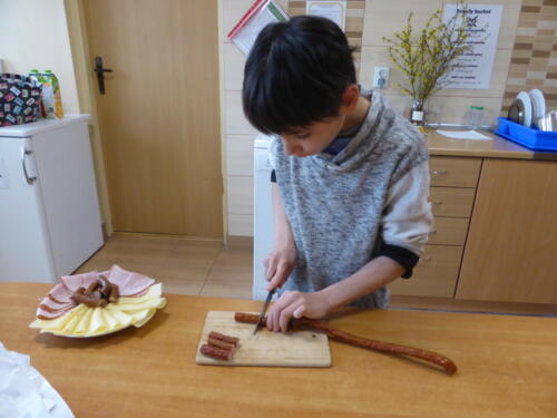 Chłopiec przygotowuje talerz z wędliną i serem