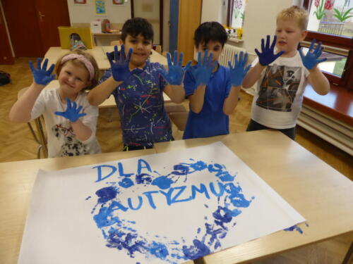 Dzieci pozują do zdjęcia, pokazując swoje dłonie pomalowane na niebiesko