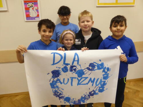 Dzieci prezentują wykonany przez siebie plakat - na nim serce utworzone z odbić dłoni, napis "Dla autyzmu"