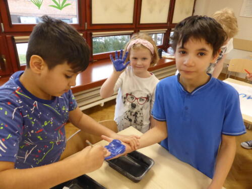 Dzieci malują swoje dłonie niebieską farbą