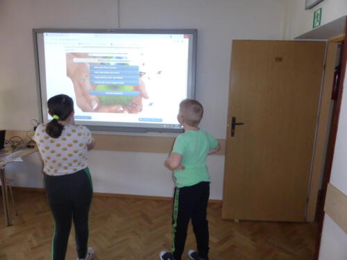 Dzieci zaznaczają odpowiedź przy tablicy multimedialnej