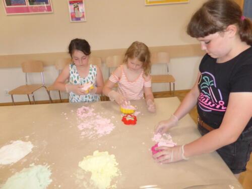 dziewczynki odciskają z piankoliny kształty za pomocą foremek do piasku