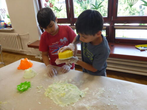 chłopcy odciskają kształty z piankoliny za pomocą foremek