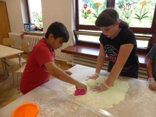 dzieci wykrawają z piankoliny kształty za pomocą foremek do ciasta