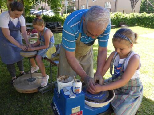 dzieci z pomocą prowadzących uczą się wytwarzać naczynia na kole garncarskim