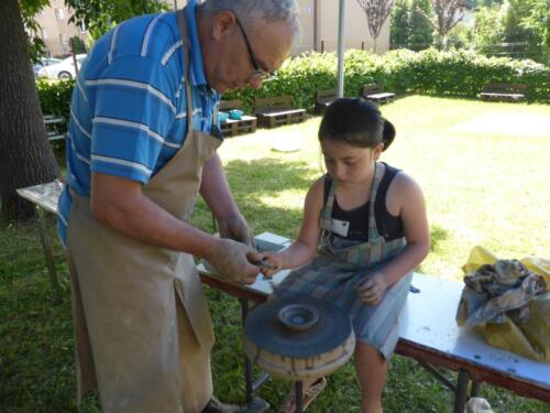 prowadzący pokazuje dziewczynce, jak zrobić naczynie na kole garncarskim
