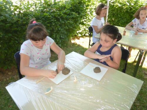dziewczynki siedzą przy stolikach, próbują ulepić coś z gliny