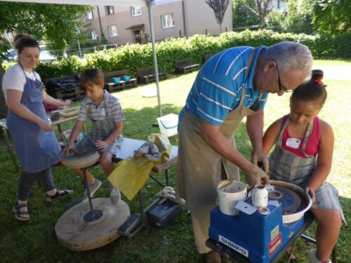 dzieci z pomocą prowadzących próbują wykonać naczynia z gliny na kole garncarskim