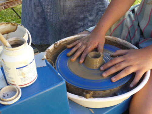zbliżenie na ręce dziecka, które tworzy naczynie na kole garncarskim