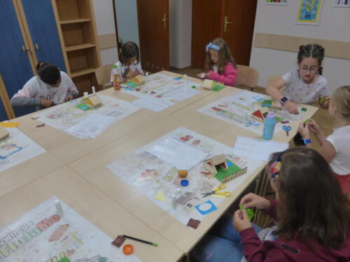 Dzieci ozdabiają zagrodę elementami z kolorowego papieru