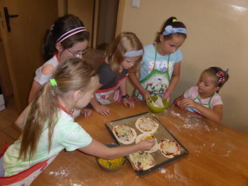 Dziewczynki nakładają składniki na pizze