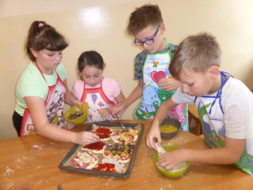 Dzieci nakładają składniki na pizze