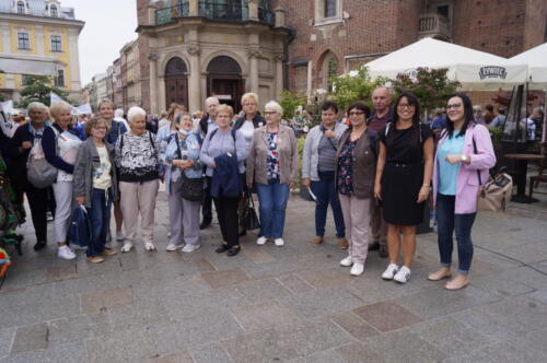 seniorzy i pracownicy OPS pozują do zdjęcia przy Kościele Mariackim w Krakowie