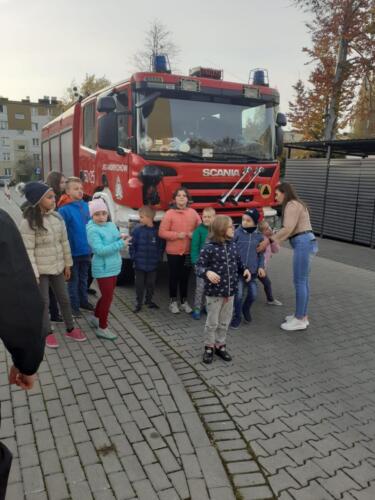Dzieci pozują do zdjęcia grupowego na tle wozu strażackiego 
