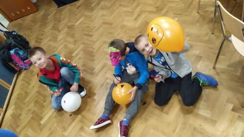 Trzech chłopców maluje upiorne buźki na balonach