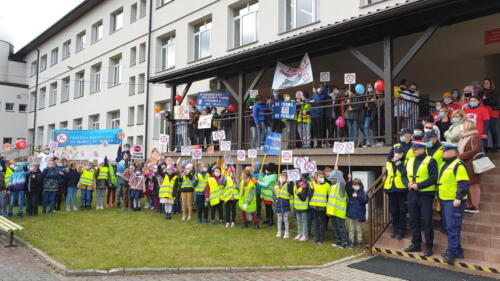 przed szkołą - na schodach, tarasie i podwórku stoją dzieci z nauczycielami i policjantami, trzymają tabliczki z logo "No promil - no problem"