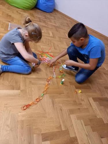 Dzieci wykonują łańcuch z kolorowego papieru 