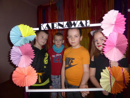 Czwórka dzieci pozuje do zdjęcia trzymając ramkę karnawałową 