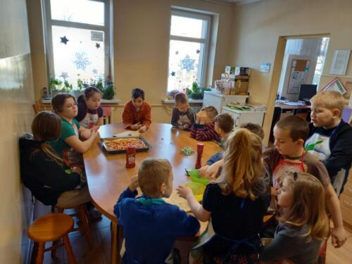 Dzieci siedzą przy stole i wspólnie gotują 