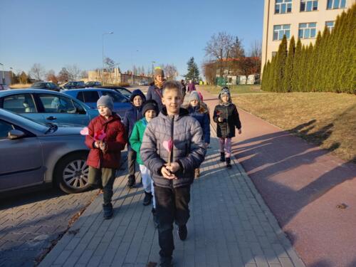 Dzieci wraz z opiekunem spacerują po Andrychowie, trzymając w rękach serduszka z papieru