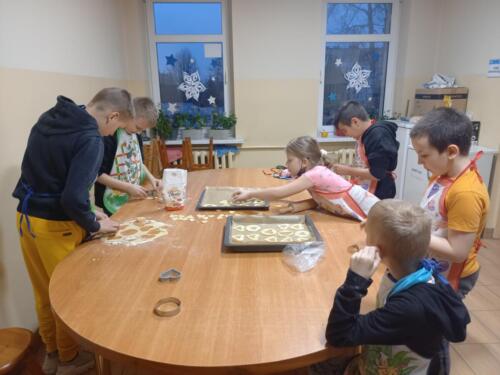 Dzieci przy pomocy foremek wycinają ciasteczka 