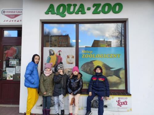 Dzieci stoją przed sklepem zoologicznym i pozują do zdjęcia grupowego 