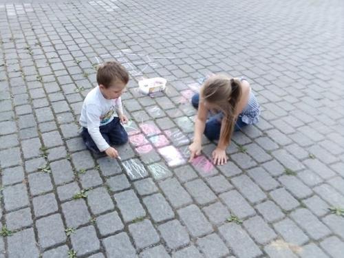 dzieci rysują kredą po chodniku