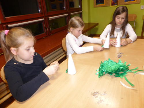 Dzieci przyczepiają kawałki wstążki do stożków ze styropianu