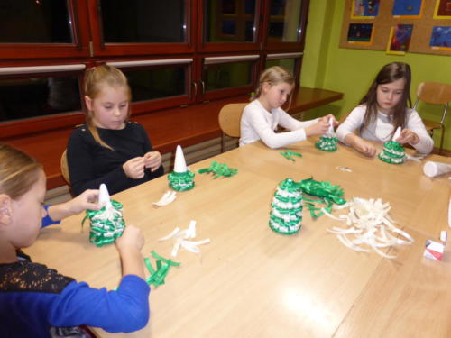 Dziewczynki robią choinki z zielonych i białych wstążek