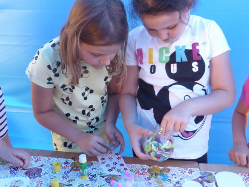 dzieci wykonują prace plastyczne z wykorzystaniem guzików